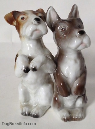 A figurine of two Jack Russell Terriers in a begging pose. They both are looking up and to the right.
