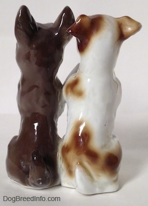The back of two Jack Russell Terrier figurines that are sitting in a begging pose. THe figurines are glossy.