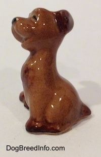 The left side of a brown Terrier puppy figurine. The figurine has its mouth open.
