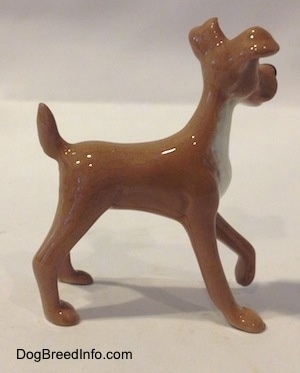 The right side of a tan with white figurine of a dog. The figurine has a medium length body.