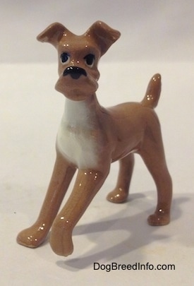 The front left side of a tan with white dog figurine. The figurine has big black eyes.