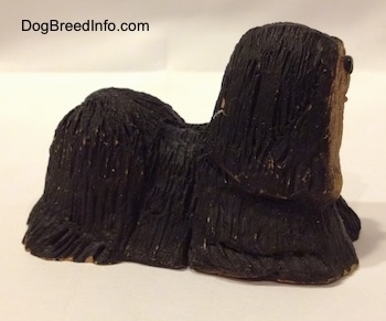 The right side of a black with tan standing Tibetan Terrier figurine. The figurine has fine hair details.
