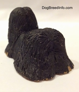 The back left side of a black with tan Tibetan Terrier standing figurine. Its hard to see the ears of the figurine.