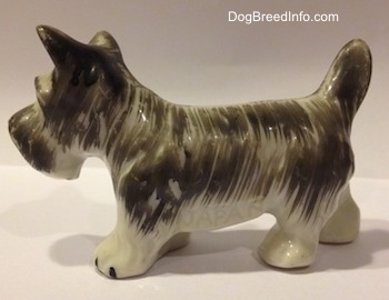 The right side of a grey and white porcelain Miniature Schnauzer figurine. The figurine has short legs.
