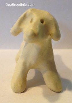 A ceramic white dog that has a holes for eyes.