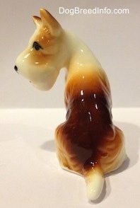 The back of a bone china figurine of a brown and white Wire Fox Terrier. The figurine is glossy.