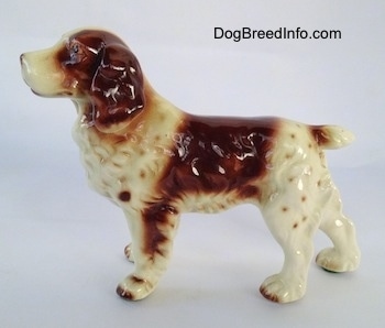 The left side of a brown and white hand-painted Welsh Springer Spaniel. The figurine has brown spots along its body.