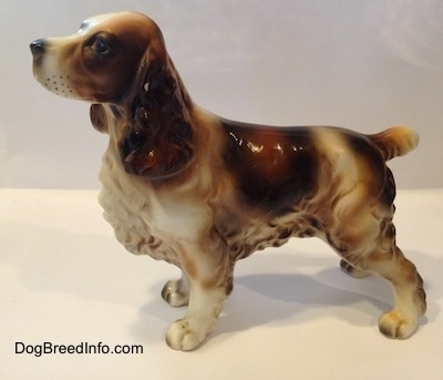 The left side of a porcelain white with brown and black Welsh Springer Spaniel standing figurine. The figurine has fine hair details along its body.
