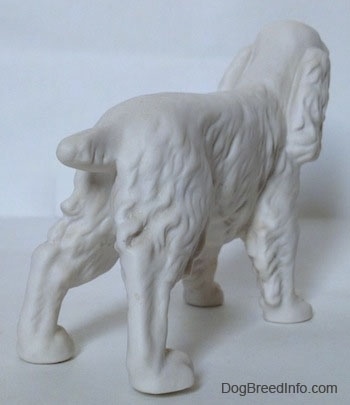 The back right side of a figurine of a white bisque unpainted Welsh Springer Spaniel figurine. The figurine has a short cropped tail.