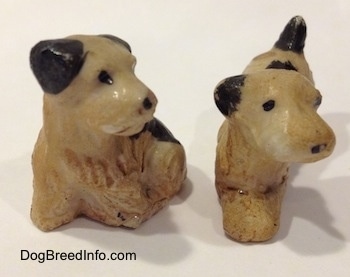 Two figurines of Welsh Terrier puppies. The figurines have black circles for eyes.