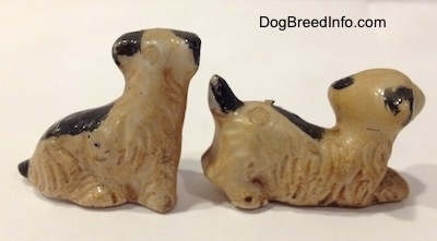 The right side of two miniature Welsh Terrier puppy figurines. The figurines have short black tails.