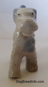 A white with blue Wire Fox Terrier figurine. The figurine has black dots for eyes.