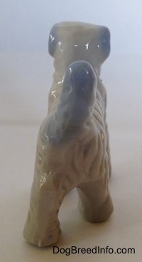 The back of a porcelain white with blue figurine of a Wire Fox Terrier. The figurine has a long blue tail.