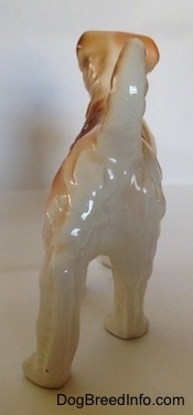 The back of a standing white and tan Wire Fox Terrier figurine. The figurine has fine hair details along its body.