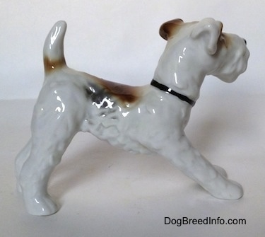 The right side of a white with black and brown figurine of a Wire Fox Terrier. The figurine has fine hair details along its body.