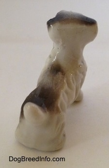 The back of a white with brown bone china figurine of a Wire Fox Terrier. The figurine has a short tail.