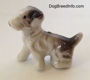 The left side of a white with black bone china figurine of a Wire Fox Terrier.