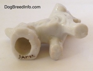 The underside of a bone china Wire Fox Terrier figurine. There is a large hole in the bottom of the figurine and under that is a black stamp that reads 'JAPAN'