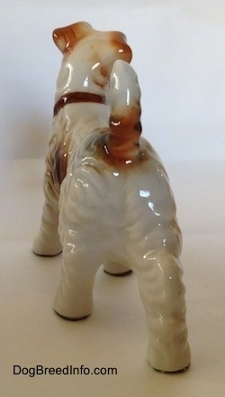 The back of a standing figurine of a Wire Fox Terrier. The figurien has a brown spot around the base of its tail.