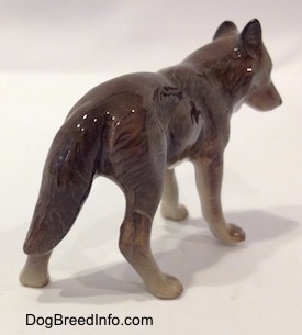 The back right side of a brown with tan Wolf figurine. The figurine has its ears in the air.