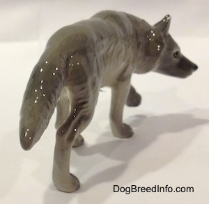 The back right side of a figurine of a stalking gray Wolf.