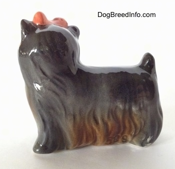 The left side of a gray with brown Yorkshire Terrier standing figurine. The figurine has short ears and a small tail.