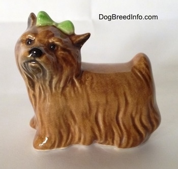 The left side of a brown Yorkshire Terrier figurine with a light green bow in its hair.