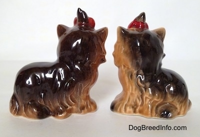 The back of two black with brown sitting figurines of Yorkshite Terriers. The figurines have fine hair details.